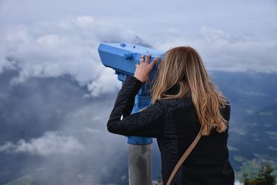 Rear view of woman looking through telescope