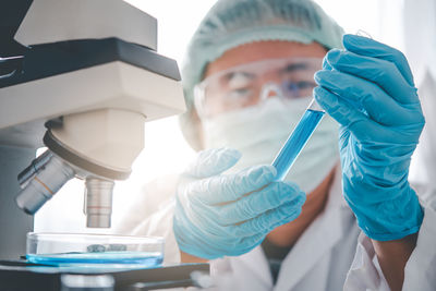 Close-up of doctor examining by microscope