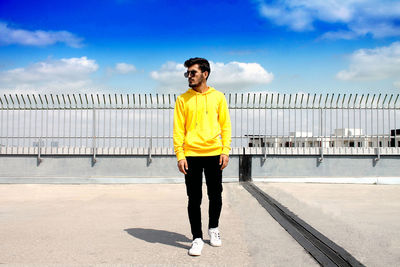 Full length portrait of young man standing against sky