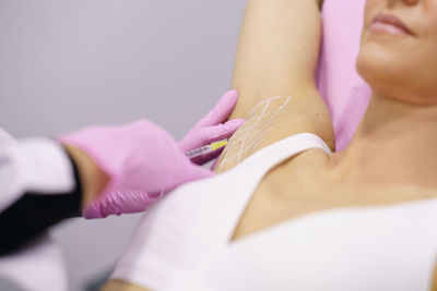 Close-up of woman hand with pink hair over white background