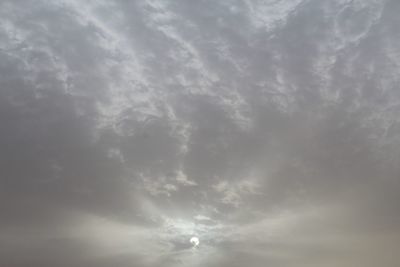 Low angle view of sunlight streaming through clouds