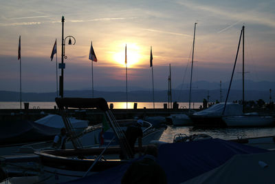 Boats moored at harbor during sunset