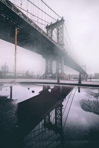 Manhattan bridge against sky in city during winter