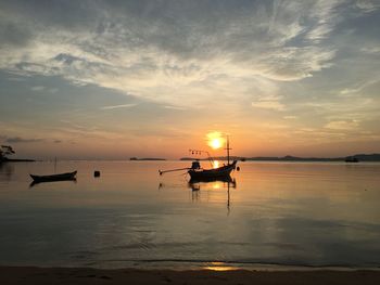 Silhouette boats in sea against sky during sunset