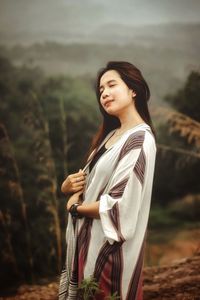 Young woman looking away while standing on land