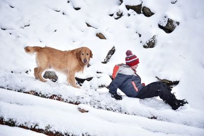Dog and boy playing on snow