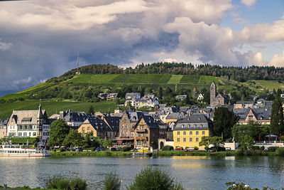 Scenic view of river by buildings against sky