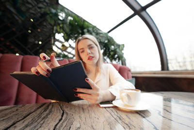 Young woman holding coffee cup on table