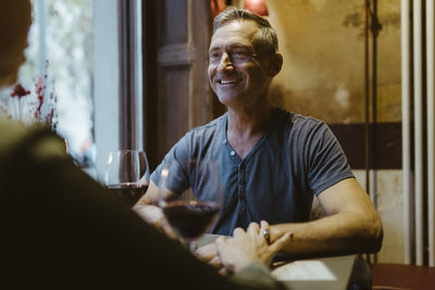 Smiling mature man having drinks with woman during date at restaurant