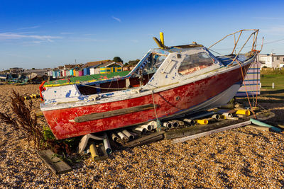 Abandoned boat on land against sky