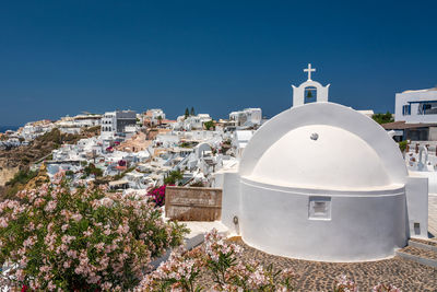 White church and buildings in city against blue sky