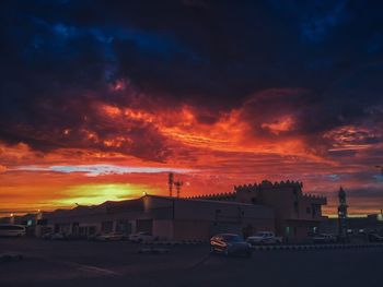 Cars on road in city against sky during sunset