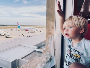 Portrait of cute boy looking through airport window