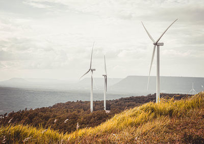 Wind turbines on field against sky