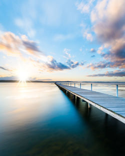 Pier over lake against sky during sunset