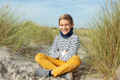 Portrait of smiling boy sitting at beach