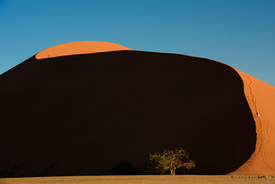 Scenic view of sand dune against clear blue sky