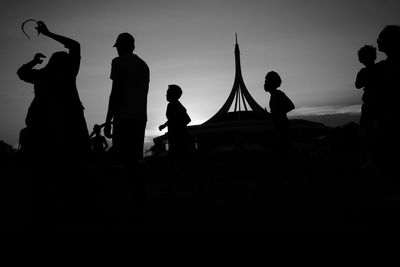 Silhouette people at music concert against sky at night