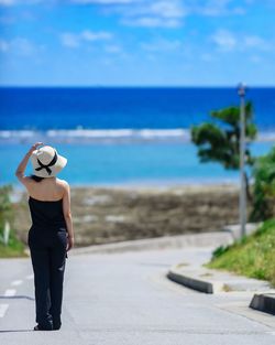 Rear view of woman on beach against sky