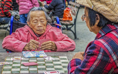 Rear view of people sitting at park during winter