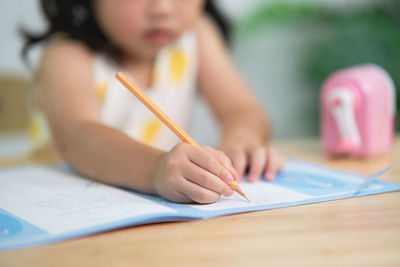 Midsection of woman writing in book at table