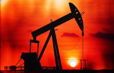 Silhouette cranes against sky at sunset