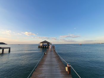 Pier over sea against blue sky