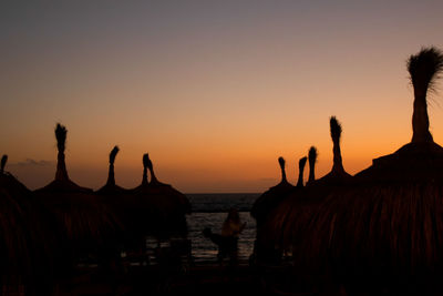 Silhouette people on beach against clear sky during sunset