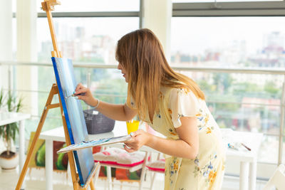 Woman painting on canvas at home