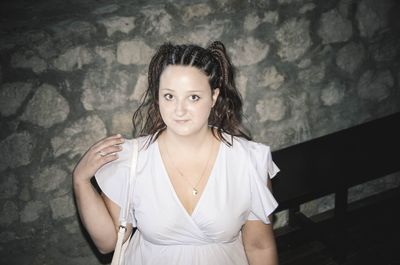 Portrait of a beautiful young woman standing against wall