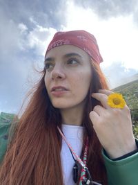 Portrait of young woman with arms raised against sky