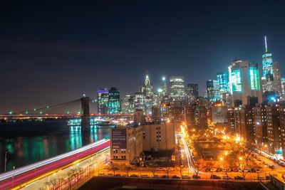 Illuminated modern buildings in city against sky at night