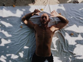 Portrait of shirtless man lying outdoors