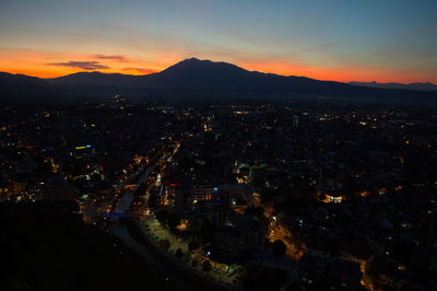 Aerial view of illuminated cityscape against sky at sunset