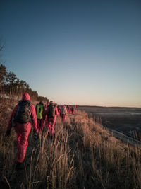 Rear view of women looking at field against clear sky