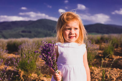 Cute girl holding flower standing on field