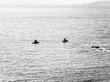 People swimming in sea against sky