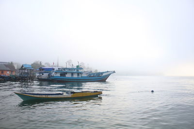 Boats in sea against clear sky