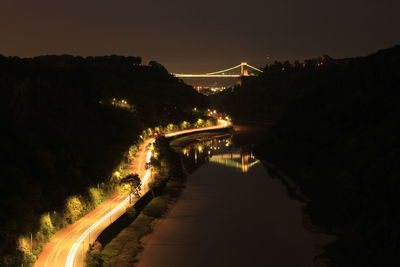 Illuminated bridge over river against sky at night