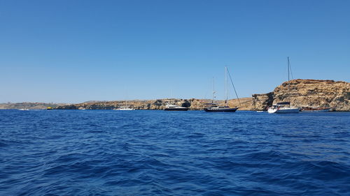 Sailboats in sea against clear blue sky