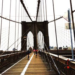 People on brooklyn bridge against clear sky