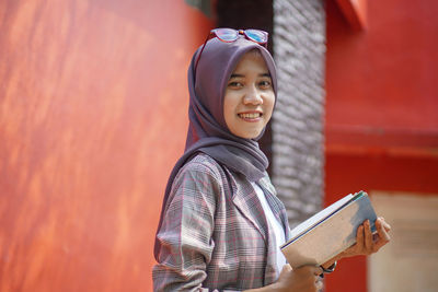 Portrait of young woman standing against wall