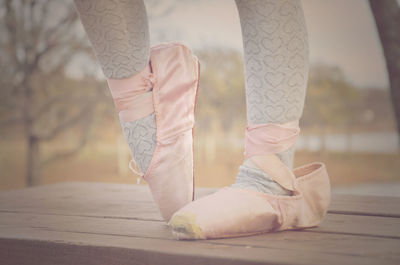Low section of girl wearing ballet shoes