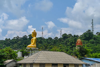 Sculpture by building against sky