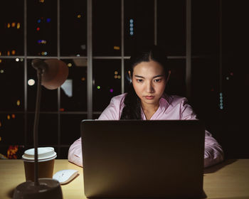 Young woman using laptop while sitting on table