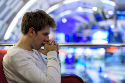 Side view of man sitting by railing