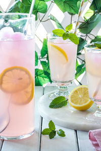 A pitcher and glasses of pink lemonade, ready for drinking.