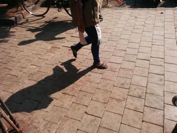 Low section of woman walking on cobblestone street