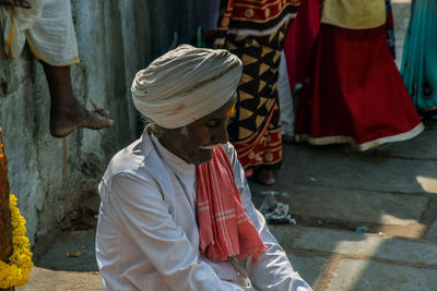 Senior man in turban sitting outdoors at market