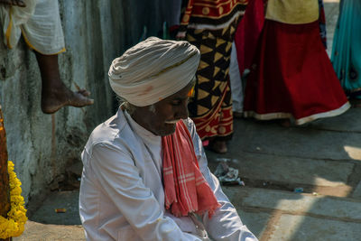 Senior man in turban sitting outdoors at market